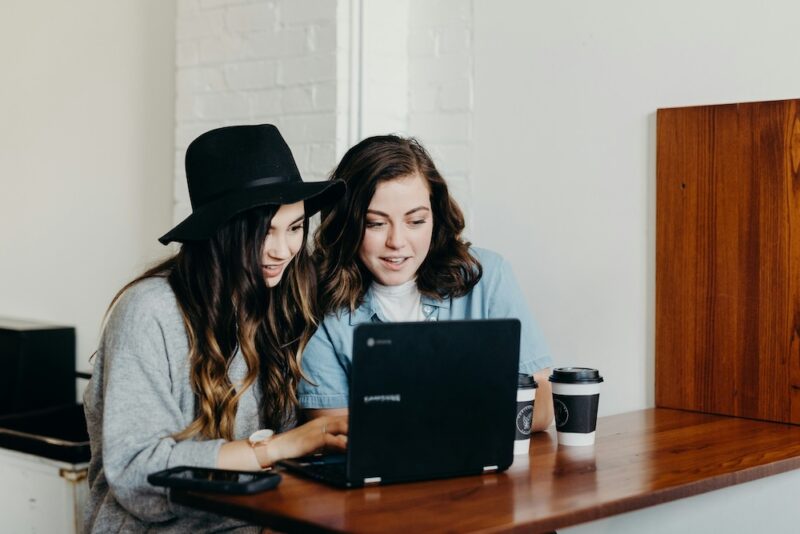 two women using their laptop at a desk.