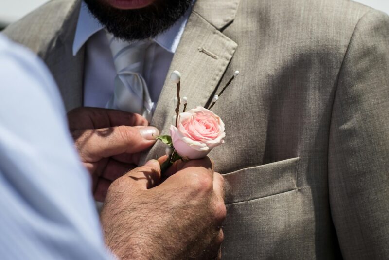 Pinning a flower on a man's suit.