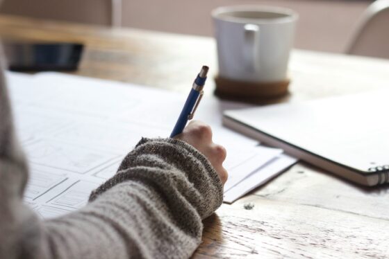 person writing with a pen and paper.