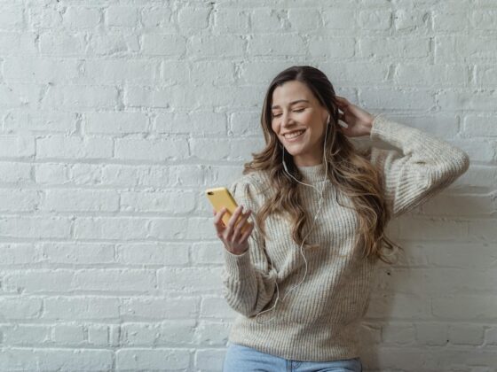 Woman using her cell phone with headphones plugged in.