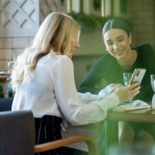 Women at a table chatting and looking at a phone