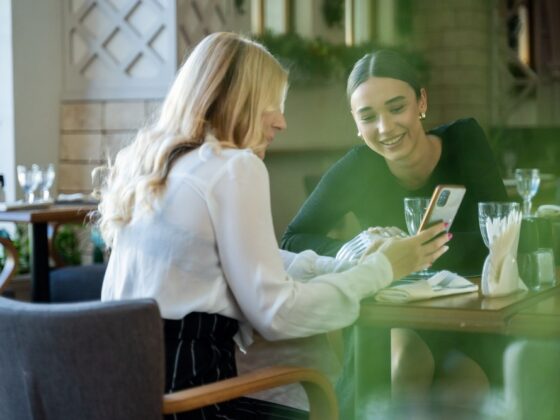 Women at a table chatting and looking at a phone