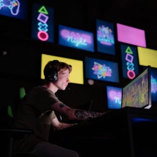Guy using a computer in a dark room with screens in the background