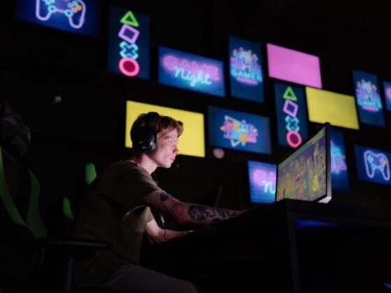 Guy using a computer in a dark room with screens in the background